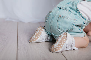 baby crawling wearing Stay-on baby booties featuring white clouds on a grey background print, with non-slip soles and adjustable three snap closure. Made from organic cotton.