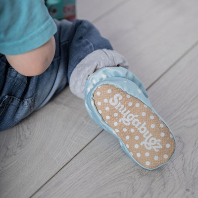 infant boy booties that stay on featuring white triangles on a baby blue background print, with anti-slip soles and adjustable  snap closure. Barefoot baby shoes made from organic cotton.