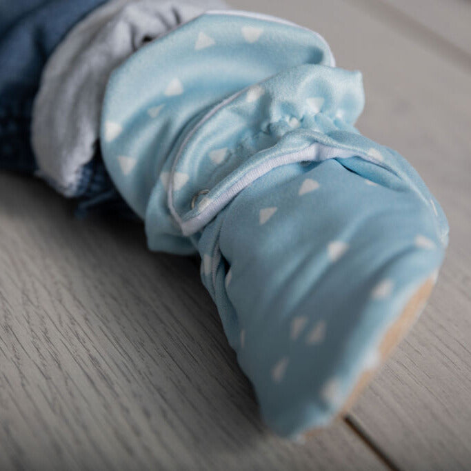 Snugabugz blue baby boy booties that stay on featuring white triangles on soft organic cotton, with non-slip soles and easy on design. Barefoot feel baby slippers