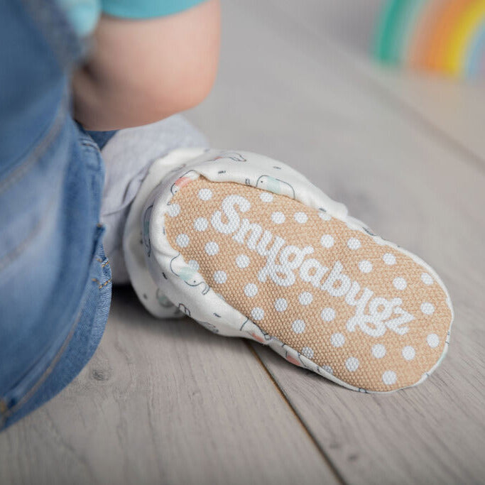 Close up shot of Snugabugz stay-on baby booties featuring a neutral elephant print on a white background, with non-slip soles and adjustable three snap closure. Made from organic cotton.