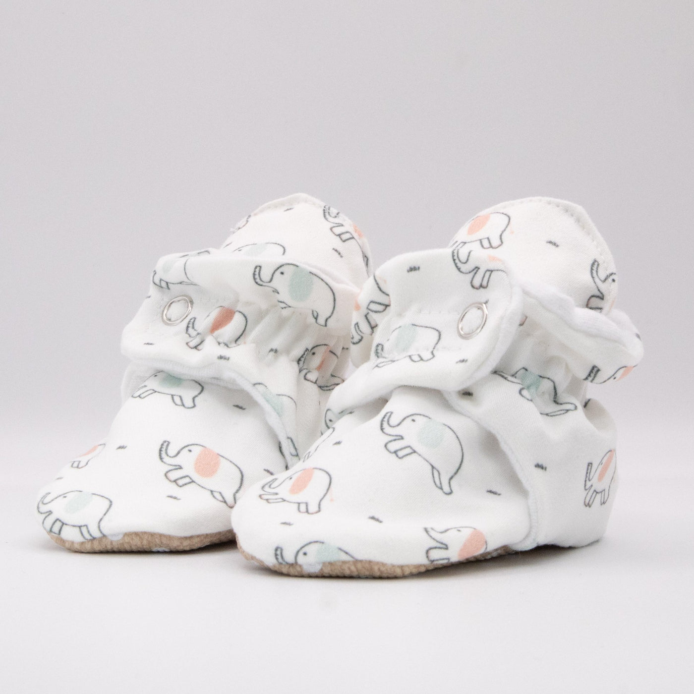 Snugabugz baby booties that stay on featuring a gender neutral newborn elephant print on a white background, with non-slip soles and adjustable snap closure. Made from sustainable organic cotton. vegan eco-friendly barefoot baby shoes